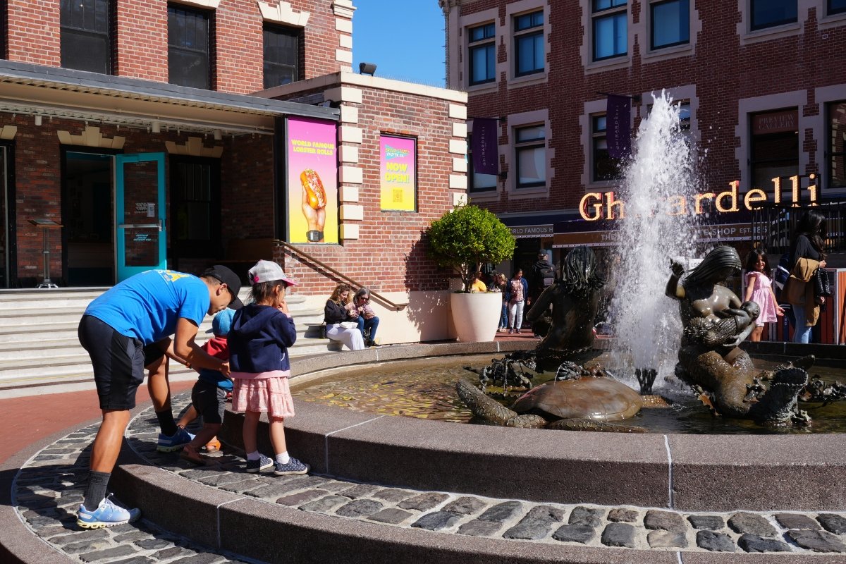 Ghirardelli Square in San Francisco with fountain, brick buildings, and visitors viewing water feature on sunny day