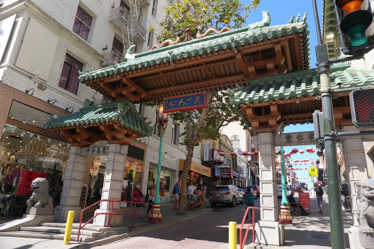 Ornate Chinatown Gate in San Francisco with green tile roof, wooden beams, and red Chinese characters, marking the entrance to the historic neighborhood.