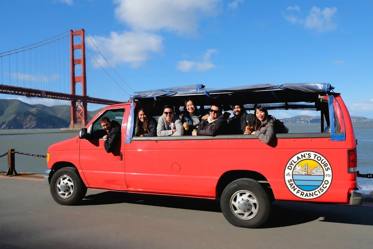 Red tour van with passengers viewing Golden Gate Bridge on sunny day in San Francisco
