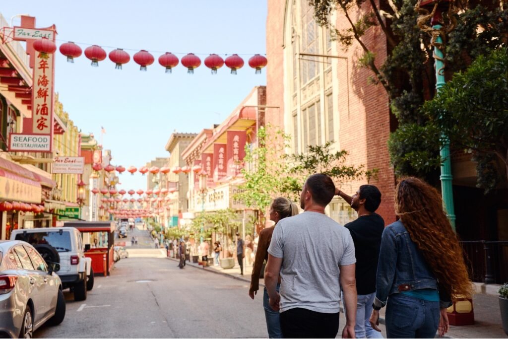 Tourists walking through San Francisco Chinatown decorated with red lanterns strung across the street