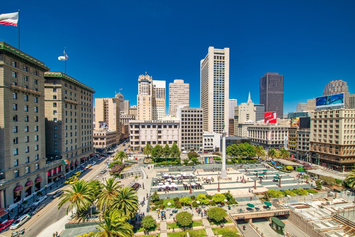 Aerial view of Union Square plaza with palm trees, surrounding hotels and downtown San Francisco buildings under blue sky