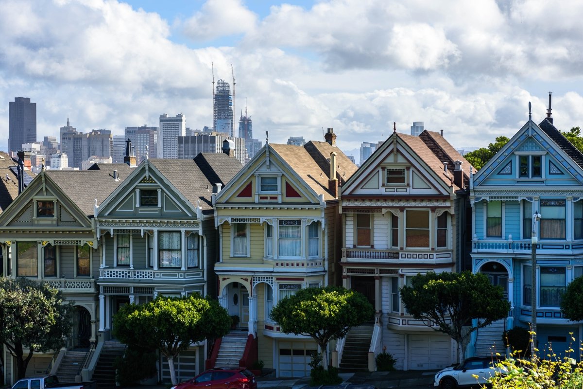Victorian Painted Ladies with San Francisco Skyline View Row of colorful Victorian Painted Ladies houses with downtown San Francisco skyline in background under blue sky with clouds