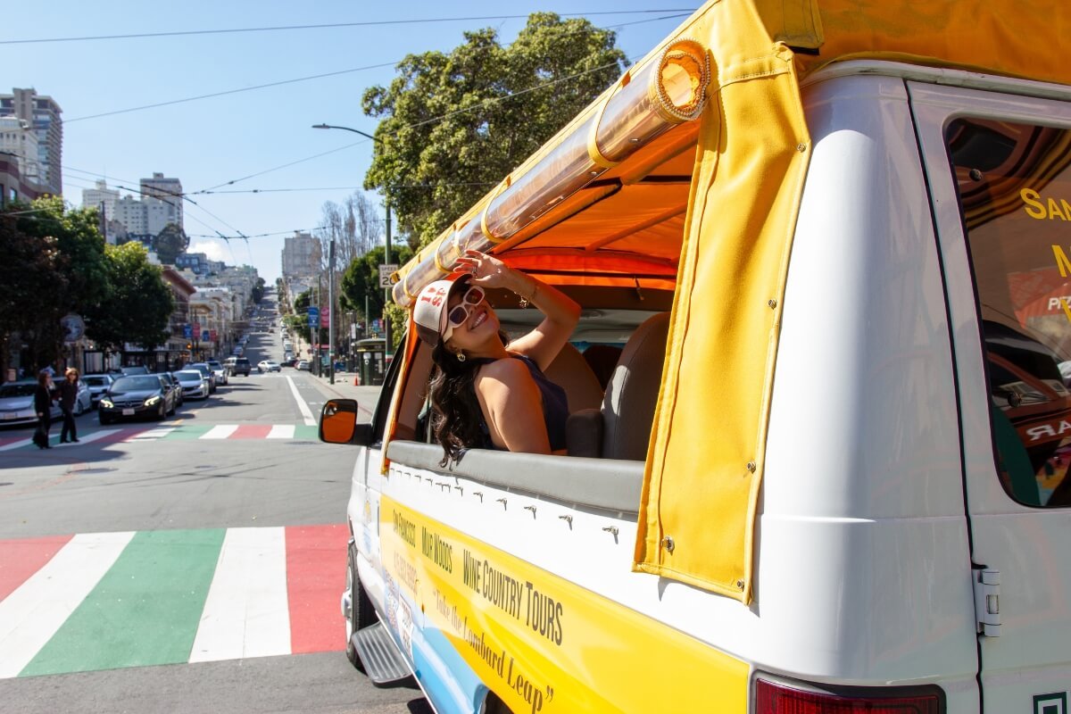 San Francisco Wine Country Tour Van on Colorful City Street Yellow and blue tour van with "Wine Country Tours" branding driving through San Francisco's hilly streets