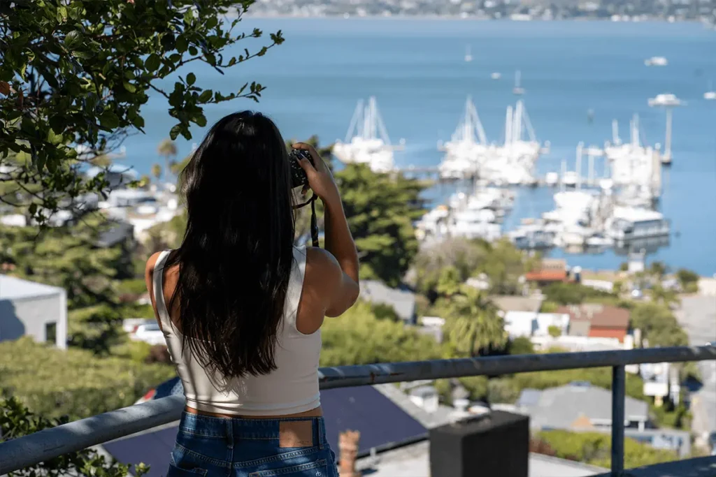 Woman taking a photo of the Sausalito pier with scenic waterfront views in the background