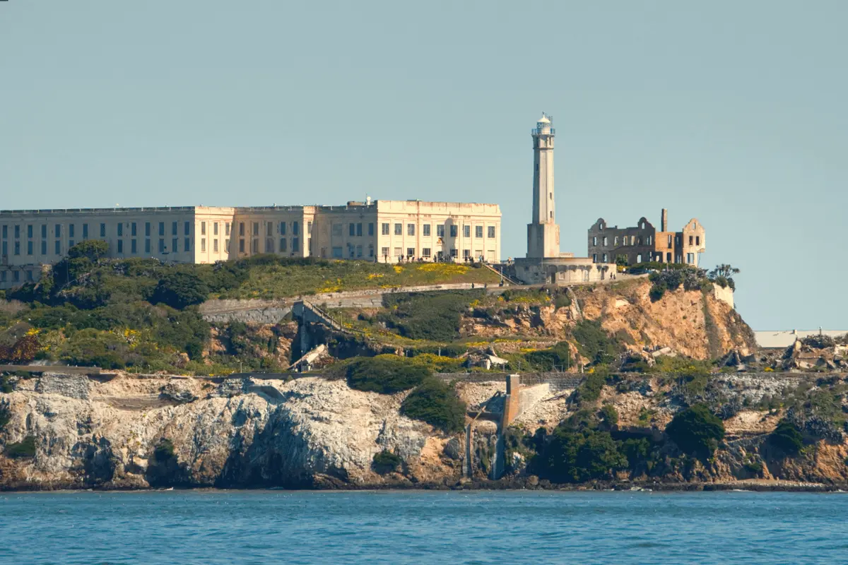A mid-range view of Alcatraz Island surrounded by blue water, with historic prison buildings visible under a clear sky