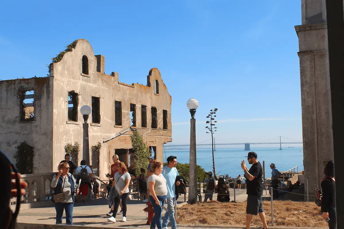 Visitors exploring historic ruins on Alcatraz Island with the Bay Bridge in the background