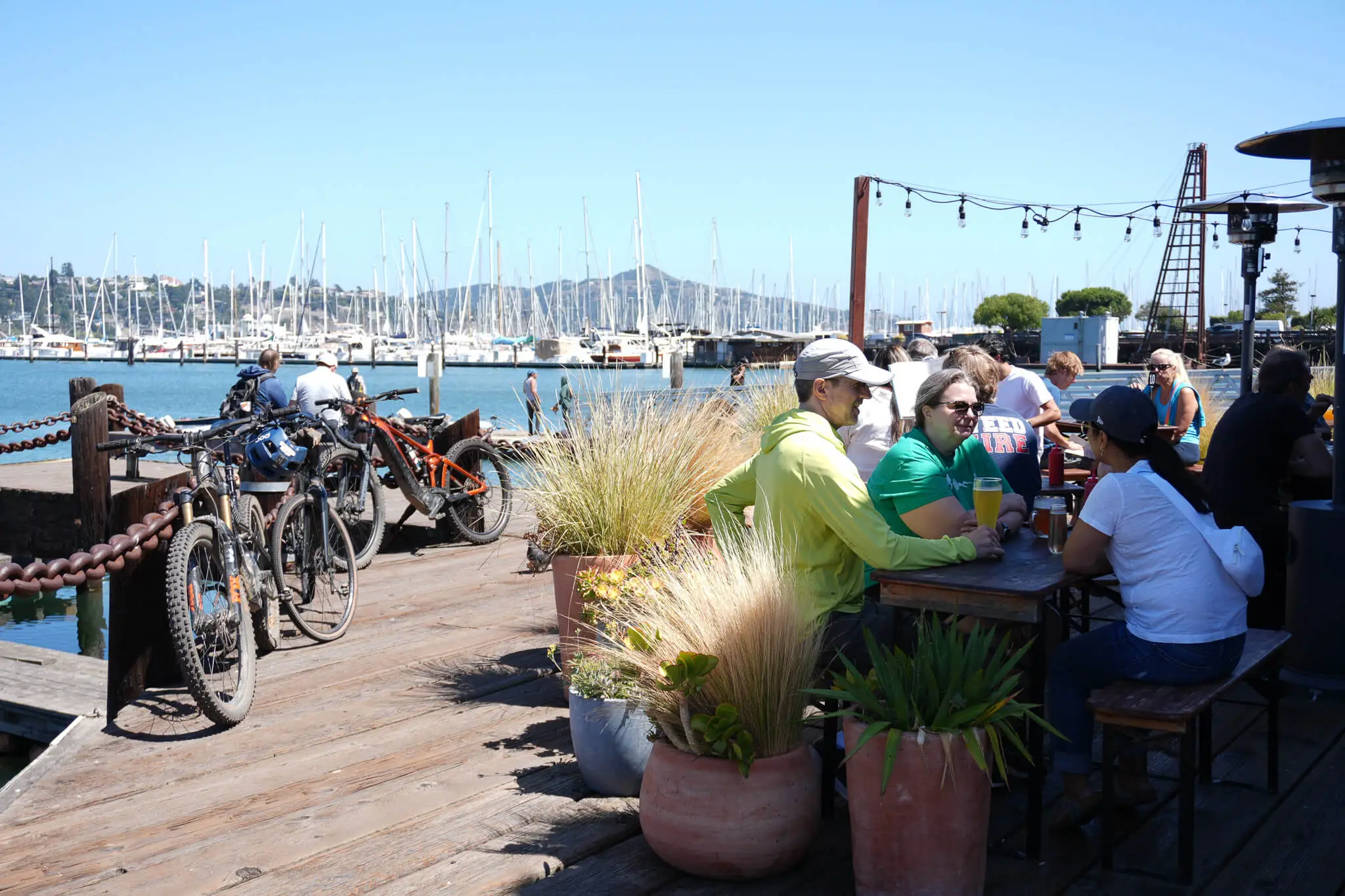 Visitors relaxing at a waterfront café in Sausalito with views of the marina and moored sailboats.